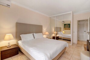 A bedroom with a bed, nightstands, a mirror, and a door. - Apartment 'Tennis View' with Private Pool, Wi-Fi and Air Conditioning (Almancil)
