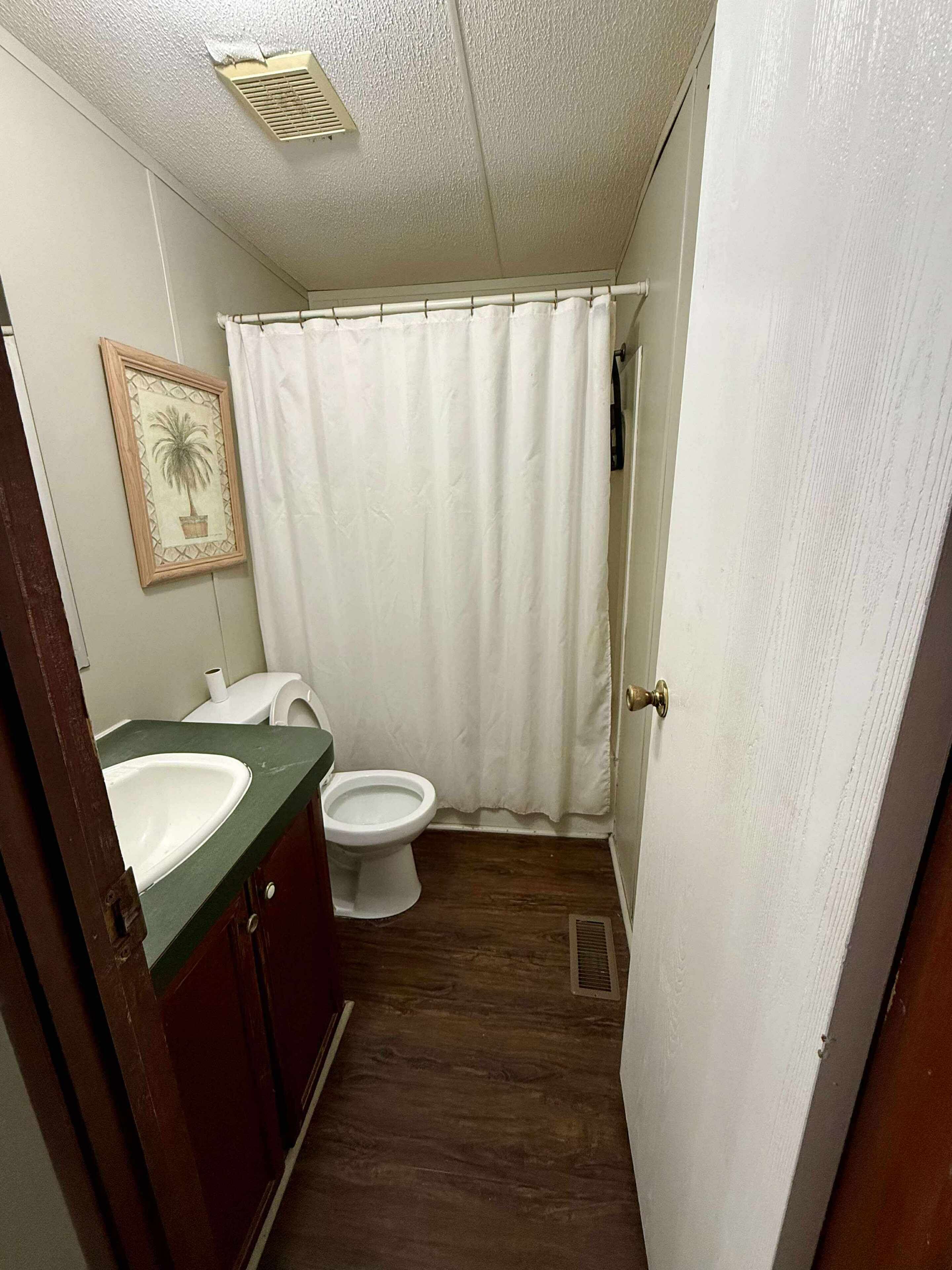 Un baño pequeño con inodoro, lavamanos y cortina de ducha.
