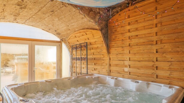 A hot tub in a rustic room with wooden walls and a sloped ceiling. - Holiday Home 'Mas Des Genêts' with Mountain View, Balcony and Wi-Fi (Laurac-en-Vivarais)