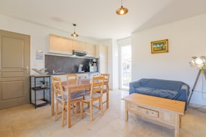 A modern kitchen with wooden cabinets, a dining table with chairs, a blue sofa, and a small side table. - Holiday Home 'Mas Des Genêts' with Mountain View, Balcony and Wi-Fi (Laurac-en-Vivarais)