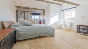 A bedroom with a bed, a chair, a desk, a window, and a door leading to another room. - Holiday Home 'Très Belle Maison' with Mountain View, Balcony and Wi-Fi (Laurac-en-Vivarais)