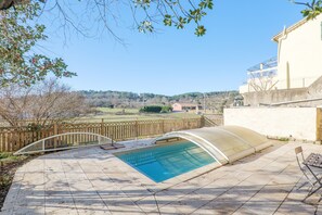 A swimming pool with a curved roof, a wooden fence, and a view of a hilly landscape. - Holiday Home 'Très Belle Maison' with Mountain View, Balcony and Wi-Fi (Laurac-en-Vivarais)