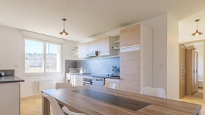 A modern kitchen with a wooden island, white chairs, and a view of the outdoors. - Holiday Home 'Très Belle Maison' with Mountain View, Balcony and Wi-Fi (Laurac-en-Vivarais)