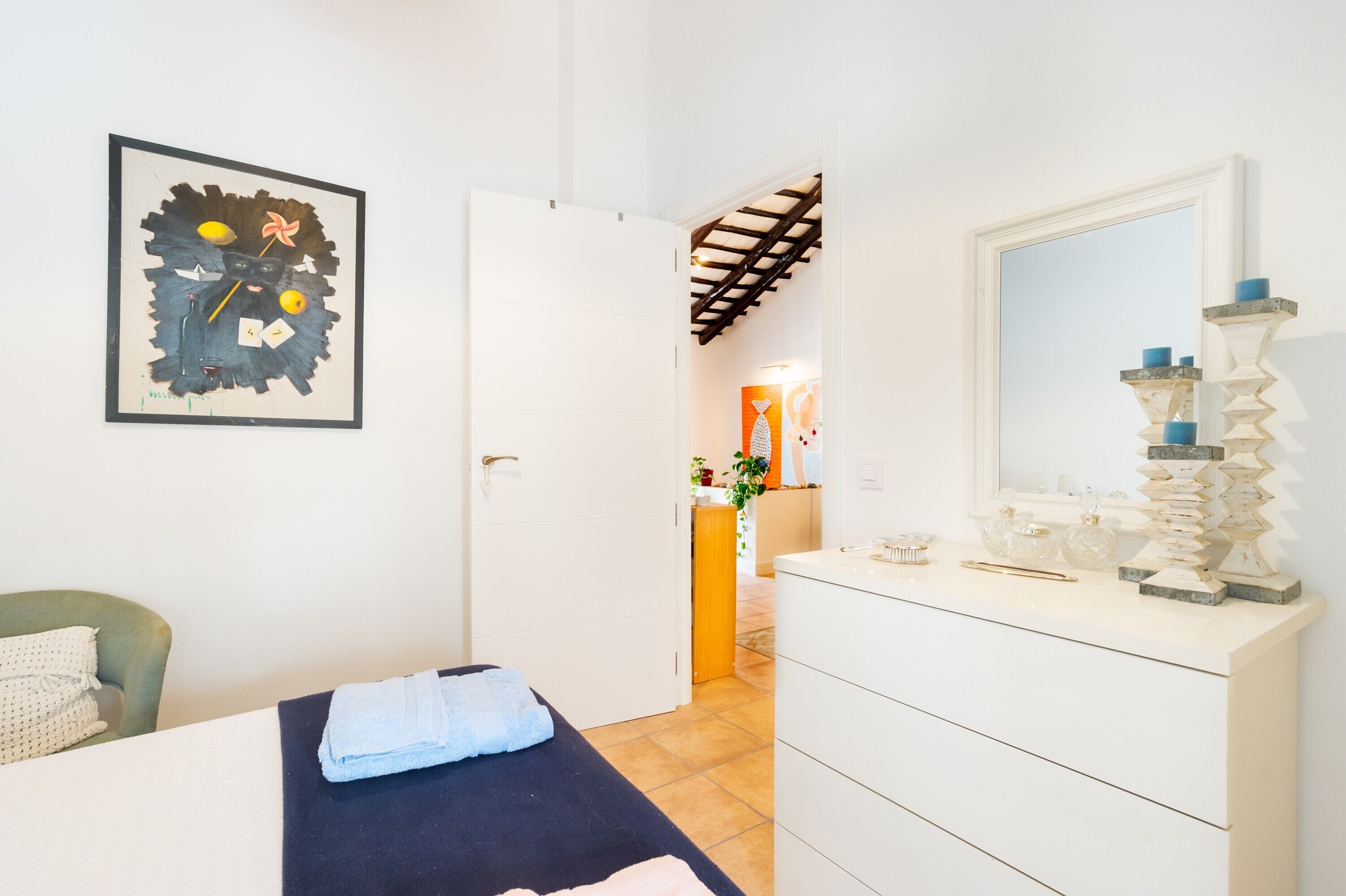 Un dormitorio con cama, cómoda, espejo y un cuadro en la pared.