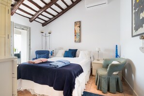 Une chambre à coucher avec un lit, une chaise, un bureau et un tableau accroché au mur.