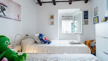 Une chambre à coucher avec un lit, une table de chevet, une lampe, un ours en peluche, un tigre en peluche et un mur décoré d’œuvres d’art.