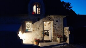 A stone building with a clock, a door, and a number 49 sign.