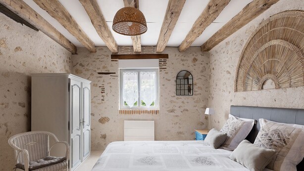 A bedroom with a bed, a chair, a wardrobe, a window, and a decorative wall piece.