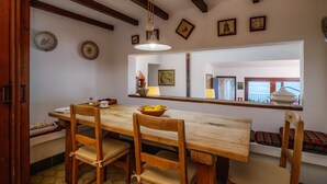 A dining area with a wooden table, chairs, a bowl of fruit, and a large mirror reflecting the room. - Villa with wi-fi and stunning sea views. (Banyalbufar)