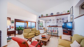 A living room with a sofa, armchairs, a TV, and a dining area with chairs and a table. - Villa with wi-fi and stunning sea views. (Banyalbufar)
