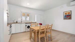 A modern kitchen with white cabinets, a wooden dining table, and a washing machine.