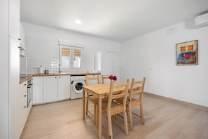 Eine moderne Küche mit weißen Schränken, einem Holzesstisch und einer Waschmaschine.