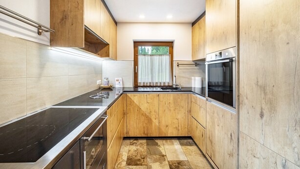 A modern kitchen with wooden cabinets, a stainless steel countertop, and a built-in oven.