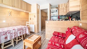 Een houten interieur met een eettafel, een bank en een kitchenette.