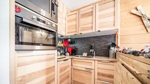 Een moderne keuken met houten kastjes, een inbouwoven en een zwarte spatwand.