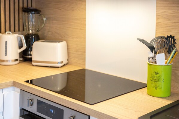 Una cocina con tostadora, licuadora y un utensilio verde en una encimera de madera.