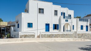 A white building with blue doors and windows, stone walls, and a clear blue sky. - Apartment 'Salonikia Studio No 3' with Sea View, Wi-Fi and Air Conditioning (Astypalaia)