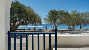 A balcony with a view of a beach, trees, and umbrellas. - Apartment 'Salonikia Studio No 3' with Sea View, Wi-Fi and Air Conditioning (Astypalaia)