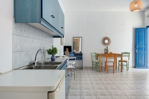Una cocina con un lavamanos, armarios y un comedor con sillas y una mesa.