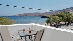 Ein Balkon mit Tisch und Stühlen mit Blick auf eine Küstenlandschaft, Schiffe und Hügel.