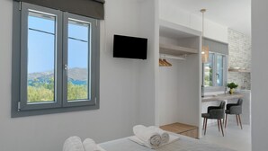 Ein Schlafzimmer mit einem Bett, zwei aufgerollten Handtüchern, einem Fernseher, einem Fenster mit Aussicht und einer kleinen Schreibtischzeile.