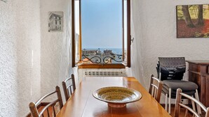 Un comedor con vista al mar, una mesa con sillas, un cuenco decorativo y un cuadro en la pared.