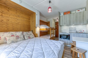 Un dormitorio con literas, un escritorio y una kitchenette.