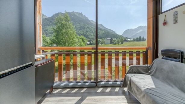 A balcony with a view of mountains, a sofa, and a bed. - Well-Equipped Studio with Enclosed Balcony and Mountain View (La Morte)