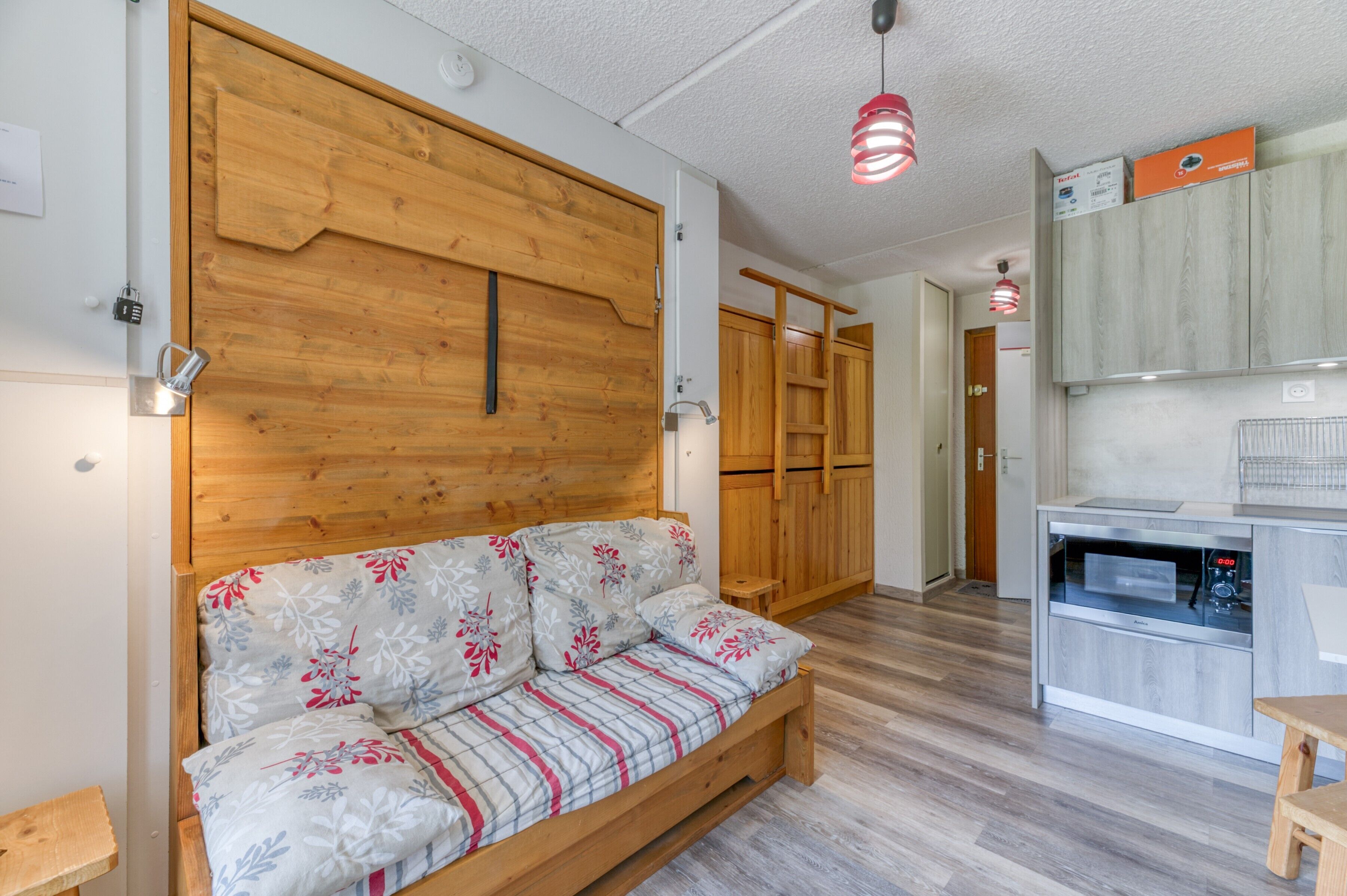 Una habitación acogedora con un sofá de madera, un área de cocina con armarios y un panel de pared de madera.
