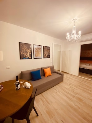 Een woonkamer met een bank, een eettafel en een kroonluchter.