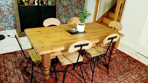 A wooden dining table with four chairs, a potted plant, and a decorative bowl.