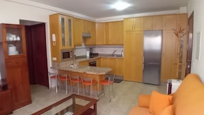 A compact kitchen with wooden cabinets, a stainless steel refrigerator, and a small dining area with stools. - Dacil - Relaxing Getaway near Beach, La Restinga (Las Puntas)