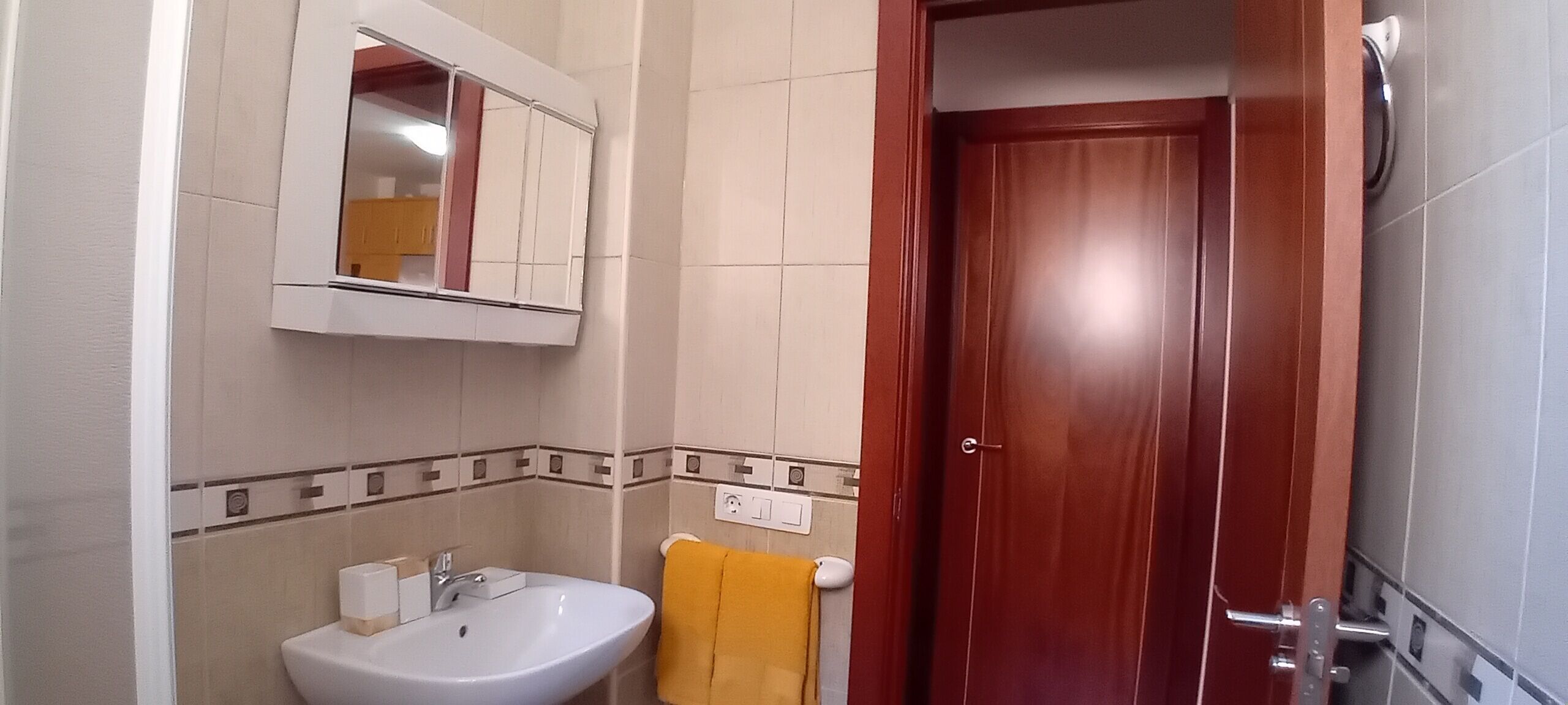 A bathroom with a white sink, a mirror, and a wooden door.