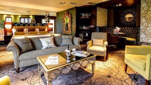 A hotel room with a sofa, armchair, and a small table with a magazine. - Cbh Ramside Hotel Golf Spa Durham (Durham)