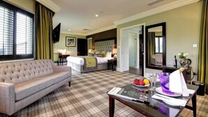 A hotel room with a sofa, a bed, a dining table with a placemat, and a television. - Cbh Ramside Hotel Golf Spa Durham (Durham)