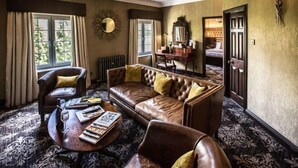 A room with a leather sofa, a wooden coffee table, a chair, a mirror, and a door. - Cbh Ramside Hotel Golf Spa Durham (Durham)