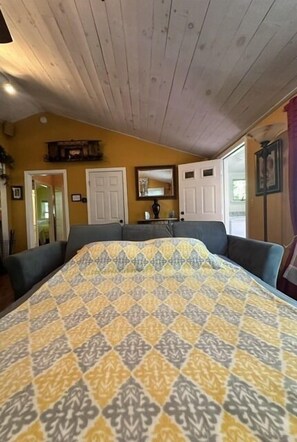A room with a bed, a wooden ceiling, a door, and a window. - Beach Pass Included! (Barnstable)