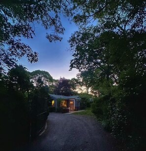 A gravel driveway leading to a building surrounded by trees. - Beach Pass Included! (Barnstable)