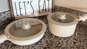 Eine Küchenarbeitsplatte mit zwei weißen Töpfen und einem Schild mit der Aufschrift 'LET'S EAT'.