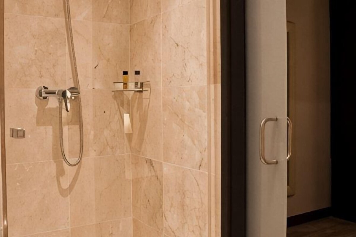 A bathroom with a shower, a towel rack, and a door with a handle.