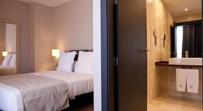 A hotel room with a bed, a bedside lamp, and a bathroom with a sink and mirror. - May Ramblas Hotel (Barcelona)