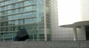 A modern building with a glass facade and a sign reading "MAGBA MUSEU D'ART CONTEMPORANI DE".