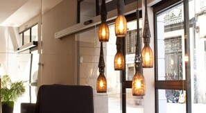 A modern interior with a seating area, large windows, and hanging pendant lights. - May Ramblas Hotel (Barcelona)