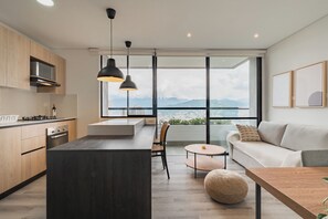 Une cuisine moderne dotée d’un îlot central, de meubles en bois et d’une grande fenêtre donnant sur la ville.