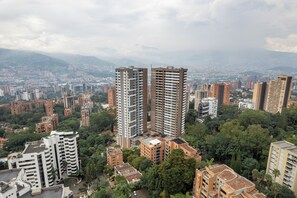 A high-rise building with multiple floors, surrounded by other buildings and greenery. - Grand By Jalo (Medellín)