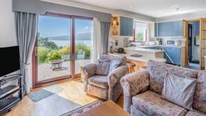 A living room with a sofa and chairs, a TV, and a view of the outdoors.