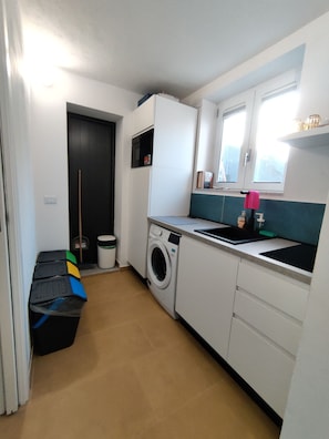 A compact kitchen with a washing machine, a sink, and a window.