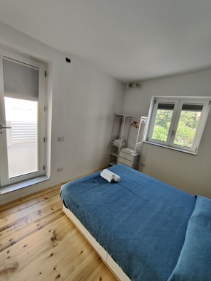 A bedroom with a single bed, a wardrobe, a window, and a door.