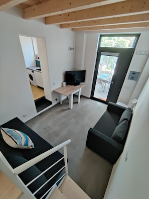 A modern living space with a sofa, a television, and a small table. There is a window providing natural light and a view of the outdoors. - Villa Mercurio, 600 meters from the beautiful beach at MONDELLO (Palermo)