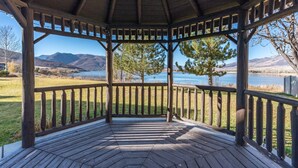 Un mirador con piso de madera y barandillas, con vista a un lago y montañas.